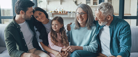 Happy multi-generation family spending time together while sitting on the sofa at home - Powered by Adobe