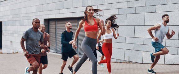 Group of young people in sports clothing jogging outdoors together
