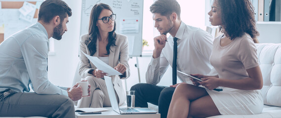 Group of young people doing some paperwork while having a business meeting in the office