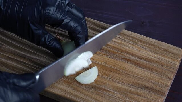 Chef cuts fresh onions with old knife into pices on wooden cutting board. Preparation of ingredients