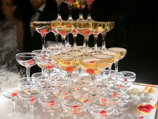 Champagne glasses standing in a tower at the wedding party. Champagne glass pyramid. Pyramid of glasses of wine, champagne, tower of champagne. Wedding party.