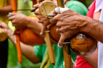 Hands of a musician playing an Afro Brazilian percussion musical instrument called a berimbau during a capoeira performance in the streets of Brazil
