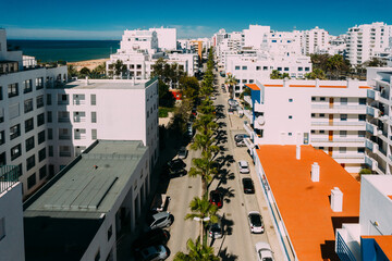 Fototapeta premium Aerial drone view of street lined with palm trees in tourist Portuguese city of Quarteira, Algarve, Portugal