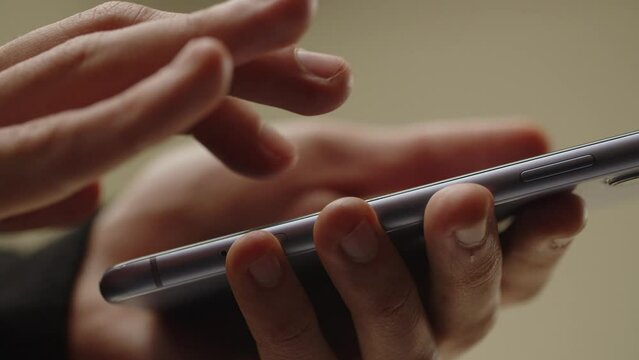 Cropped view of male hands tapping on smartphone screen. A man looks through the news on his smartphone, scrolls the social media feed.
