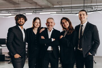 Diverse business team in black costumes. Indoor shot of business partners looking at camera with smile. Business opportunities, career growth