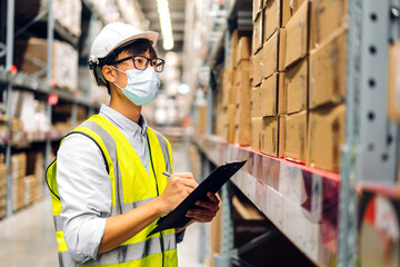 Portrait asian engineer man shipping order detail on clipboard check goods and supplies on shelves with goods background inventory in factory warehouse.logistic industry and business export