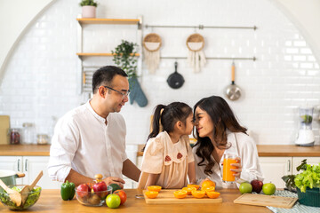 Portrait of enjoy happy love asian family father and mother with little asian girl preparing drinking glass of fresh juice and orange on counter in kitchen at home.Diet concept.healthy drink