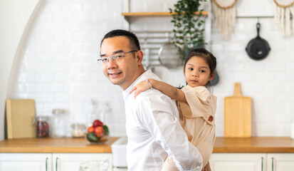 Portrait of enjoy happy love asian family mature father hold little girl daughter on back smiling play laughing and having fun together.happy family and father's Day in moments good time at home