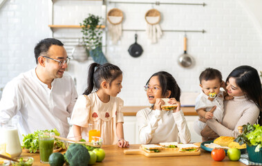 Portrait of enjoy happy love asian family father and mother with little asian girl daughter child having fun help cook food healthy eat with fresh vegetable salad and sandwich ingredient in kitchen