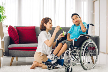 Portrait of enjoy happy love family asian mother playing and carer helping look at disabled son child sitting in wheelchair moments good time at home.disability care concept.