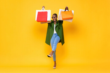Full body studio shot portrait of fashionable African-American woman carrying shopping bags on...