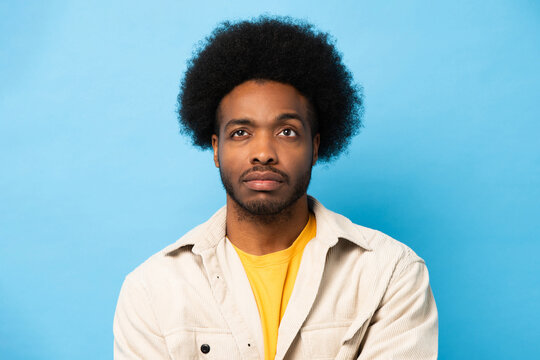 Afro African American man thinking and looking up in light blue color isolated studio background