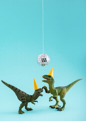 Two cute green dinosaurs dancing under disco ball. Funny idea for birthday card on blue background.
