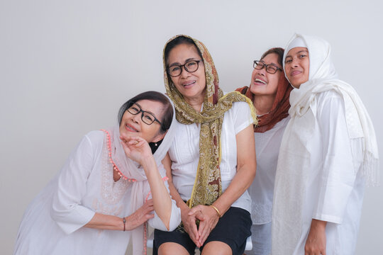 A group of four women in white are enjoying each other's company.