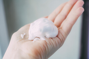 Naklejka premium gentle foam on the hand of a female hand, hygiene and skin care, soap foam on the palm