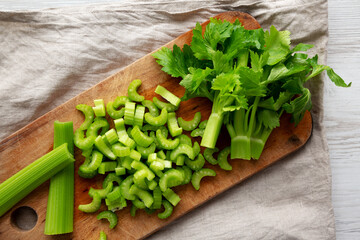 Raw Green Organic Celery on a rustic wooden board, top view. Flat lay, overhead, from above.