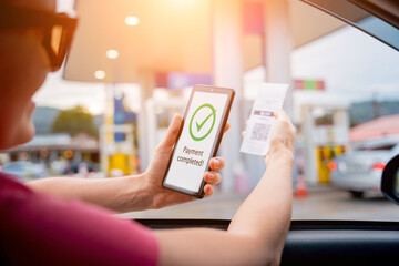 Woman using contactless payment by mobile phone with QR code at car filling station