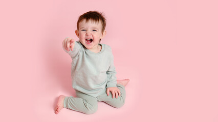 Happy toddler baby on studio pink background, copy space. Emotional child boy with a smile on his face, full height. Kid age one year eight months