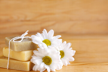 Obraz na płótnie Canvas Bars of soap and chamomile flowers on wooden background