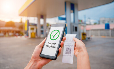 Woman using contactless payment by mobile phone with QR code at car filling station