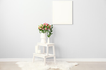 Vase with beautiful alstroemeria flowers and candles on step ladder near light wall © Pixel-Shot