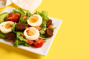 Plate of delicious salad with boiled eggs and salmon on yellow background