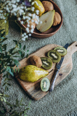 still life of pear and kiwi on the table with a vase of flowers