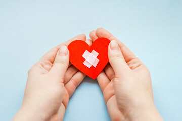 health day. close up of female hands with medical cross on a small red paper heart