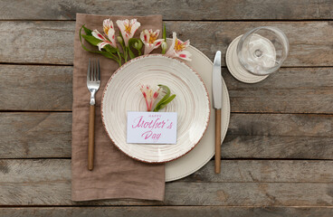 Table setting for Mother's Day celebration with alstroemeria flowers on wooden background