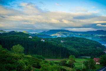 landscape with forest and mountains, in the background mountain peaks in the clouds. Basque Country, Spain.