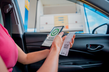 Woman using contactless payment by mobile phone with QR code at car filling station