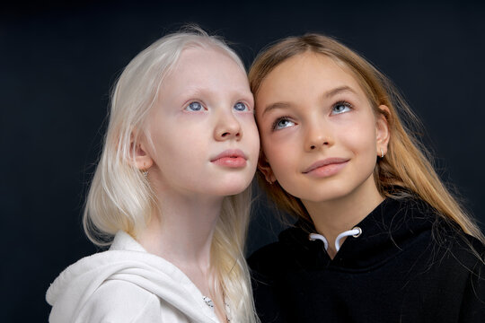 two good looking girls dreaming looking up isolated black background. friends make up plan, decission