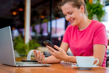 Woman using contactless payment by mobile phone with QR code at cafe