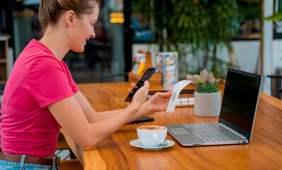 Woman using contactless payment by mobile phone with QR code at cafe
