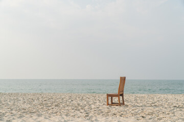 Fototapeta na wymiar A chair with no people on the sea beach in front of a minimalist background. relax on lonely beach. sea sand sky concept. summer vacation. copy space.