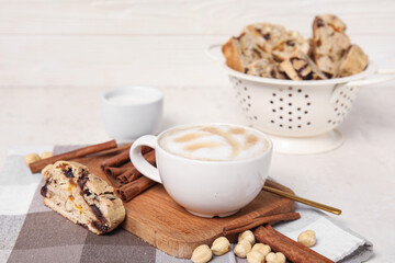 Board with delicious biscotti cookie, hazelnuts and cup of coffee on napkin