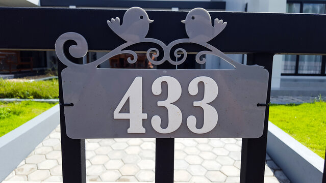 Number on gray plastic plate installed on the black metal gate