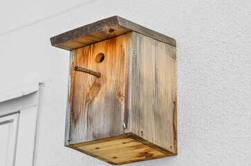 Wooden bird house on white wall outdoors