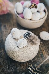 White and pink chocolate eggs and pink tulips on rustic wooden table.