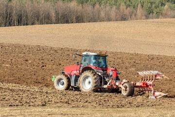 Tractor plowing fields. Spring work on the farm in the Czech Republic. Agricultural landscape. Preparation for sowing grain.