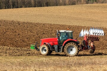 Tractor plowing fields. Spring work on the farm in the Czech Republic. Agricultural landscape. Preparation for sowing grain.