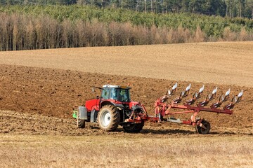 Tractor plowing fields. Spring work on the farm in the Czech Republic. Agricultural landscape. Preparation for sowing grain.