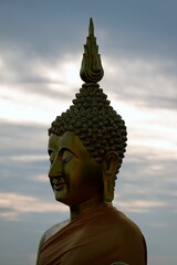 Vertical aerial view of the head of big golden Buddha statue on the top of a mountain