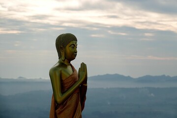 Aerial shallow focus shot of big golden Buddha statue on the top of a mountain