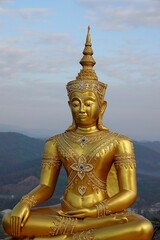 Vertical aerial view of big golden Buddha statue on the top of a mountain