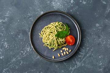 Plate with tasty pesto pasta and tomatoes on dark grunge background