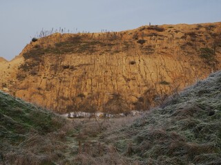 Eroding mountain and a valley with frozen grass under the blue sky