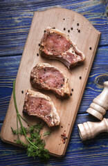 Pieces of raw pork  with spices ,  salt and pepper on blue wooden background in rustic style. top view