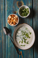 yogurt soup with herbs and crackers on a blue wooden table,top view