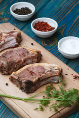 Raw pork meat and ingredients on a board on blue desk